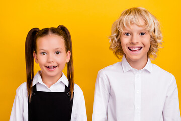 Photo of two funny positive schoolkids shiny white smile wear school uniform isolated yellow color...