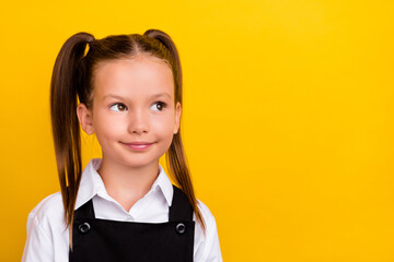 Photo of dreamy thoughtful schoolgirl look up empty space wear school uniform isolated yellow color...