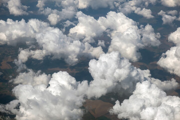 Aerial view from airplane window of white puffy clouds on bright sunny day.