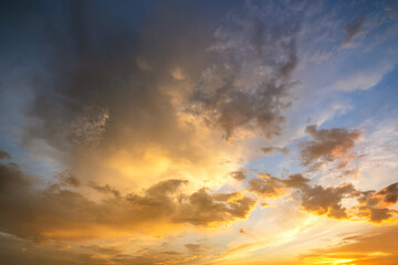 Naklejka na ściany i meble Dramatic sunset sky landscape with puffy clouds lit by orange setting sun and blue heavens.