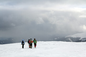 Back view of hikers walking on snow covered hill in winter mountains. - Powered by Adobe