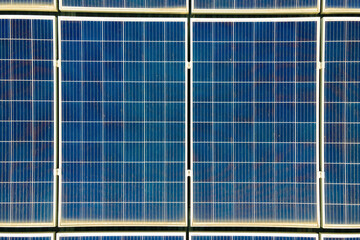 Closeup of surface of blue photovoltaic solar panels mounted on building roof for producing clean ecological electricity.