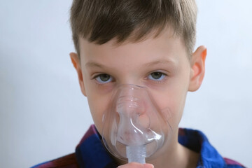 Portrait of child teen boy is breathing in mask using nebulizer for inhalation procedure at home....