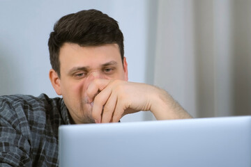 Portrait of sick young man is using nebulizer and inhaler for treatment at home and working on laptop. He is breathing in mask. Fibrosis, covid-19, asthma copd. Treatment, cure and procedure, therapy.