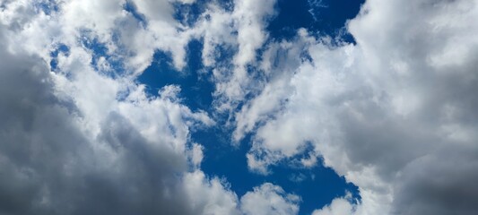 Light gray clouds on the blue sky. Several clouds merge into a cloud, from below the gray clouds...