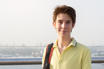 Young handsome 15 years old teen boy looking at camera and happy smiling over panorama of Kyiv and...