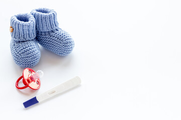 Pregnancy test and blue baby boy booties. Morherhood and pregnancy concept