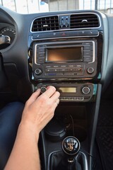 Fototapeta premium The driver, whose face is not visible, turns on the air conditioner in the car against the background of the dashboard