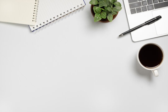 White desk  with Laptop, blank notepad, flower, coffee cup and pen. Flat lay top view copy space.