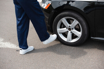 Cropped view of mechanic in overalls standing near wheel of car