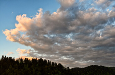 Obraz premium Clouds over the Ochotnica Gorna vilage hills during summer day