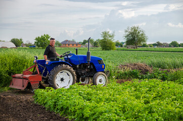 Obraz premium A farmer on a tractor works in the field. Seasonal worker. Recruiting and hiring employees for work in the farm. Milling soil. Agribusiness and agroindustry. Loosening , cultivation. Plowing