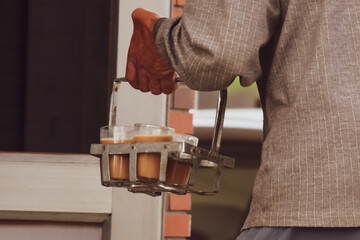 closeup hand holding tea glasses in the stand