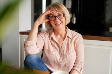 Portrait of happy senior woman sitting at table at home