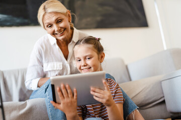 White mother and daughter using tablet computer together at home