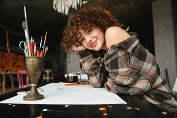 Smiling young redhead woman artist drawing