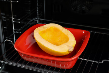 Baking dish with half of fresh spaghetti squash in oven