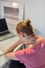 Woman working from home on a laptop and having pain in the neck.
