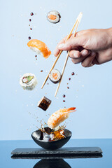 Flying pieces of sushi on blue background.  Vertical format. © Miguel Tamayo 