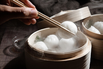 Hand picking dim sum from bamboo steamer.
