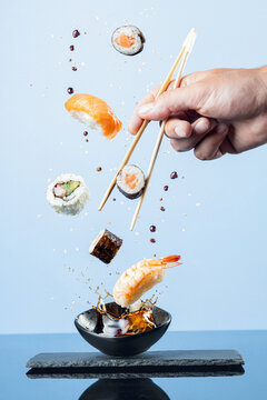Flying pieces of sushi on blue background.  Vertical format.