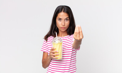 young hispanic woman making capice or money gesture, telling you to pay and holding a vanila...
