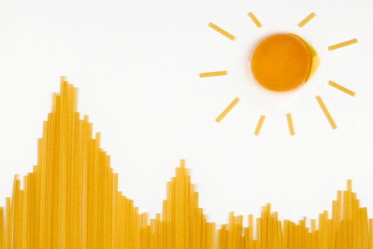 Uncooked spaghetti in shape of hills and egg as sun. Travel snack concept