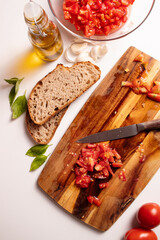 Cutting fresh tomato and preparng homemade bruschetta with olive oil, garlic and basil