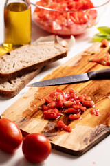 Cutting fresh tomato and preparng homemade bruschetta with olive oil, garlic and basil