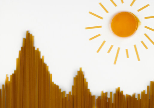 Uncooked spaghetti in shape of hills and egg as sun. Travel snack concept