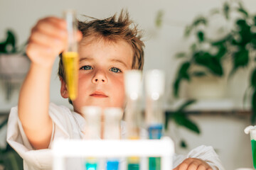 Serious little boy in white uniform conducts chemical experiments in a laboratory.Back to school...