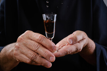Close up of hands elderly woman holding shot glass or wineglass sedative drops or cognac ....