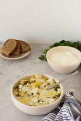 Chicken breast and sorrel soup with potatoes and sour cream, a bowl of soup on the table, bread and parsley