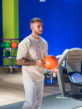 Hombre joven con tatuajes jugando a los bolos