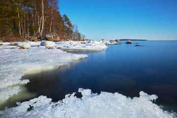 Before sunset at the end of winter in Uutela near Helsinki pretty snow-white ice floe melts against...