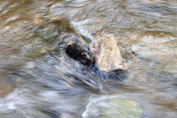 Strumyk z płynącą wodą między kamieniami. - obrazy, fototapety, plakaty