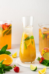 Fototapeta na wymiar Jugs of fresh refreshing fruit drinks with fruit wedges, summer cold juices with ice