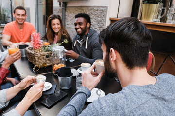 Happy diverse friends eating and drinking coffee outdoor at vintage bar restaurant - Main focus on right man head
