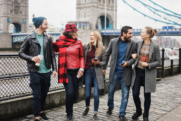 Young friends having fun outdoor at the city with Tower Bridge in London in background - Focus on...