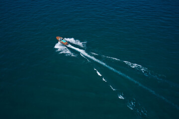Luxurious wooden boat fast movement on dark water. Classic Italian wooden boat fast moving aerial view. Top view of a wooden open large motor boat.
