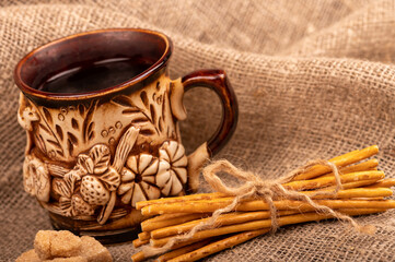 Breadsticks with salt tied with string and an earthenware mug for tea. Close-up Selective focus.