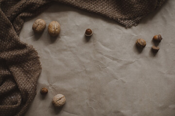 autumn theme, brown paper texture background with cozy warm plaid, walnuts and acorns, top view, copyspace