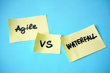 waterfall vs agile paper task on blue background, software development methodologies concept