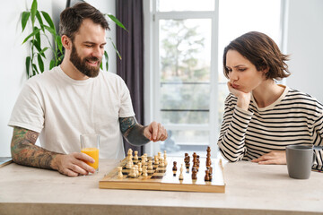 Happy young white couple playing chess