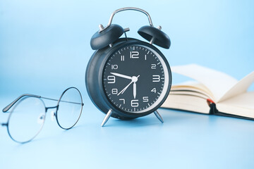 alarm clock , eyeglass and book on table 