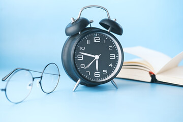 alarm clock , eyeglass and book on table 
