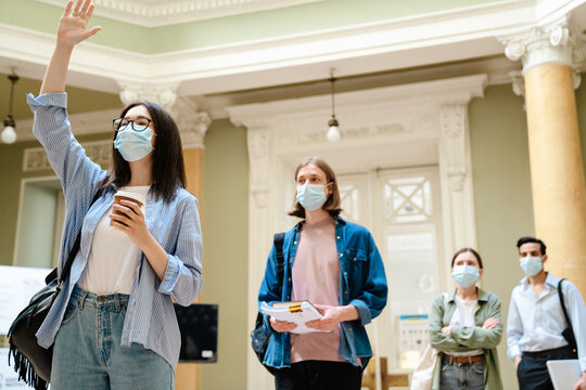 Young european students in face mask standing in line at library entry