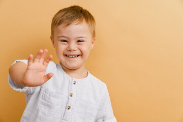 White boy with down syndrome smiling and gesturing at camera - obrazy, fototapety, plakaty