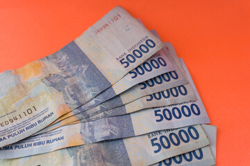 Obraz premium The Indonesian currency is rupiah, which is very much scattered and is worth fifty hundred thousand rupiah. Isolated in orange. For illustrations of news with the theme of economy, buying sell.