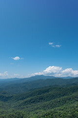 Forest covered foothills of the Blue Ridge Mountains on North Carolina, NC, USA with brilliant blue sky and puffy white clouds